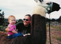 Child sitting on Sparky the llama